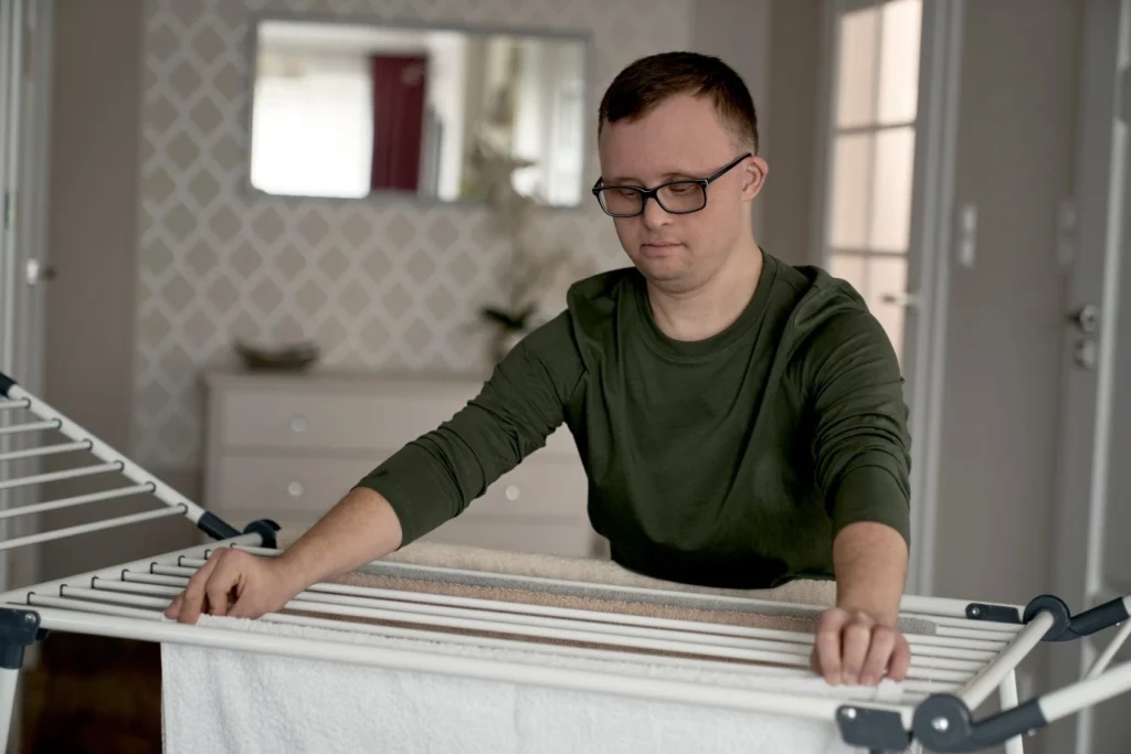 Man with down syndrome hanging laundry at home