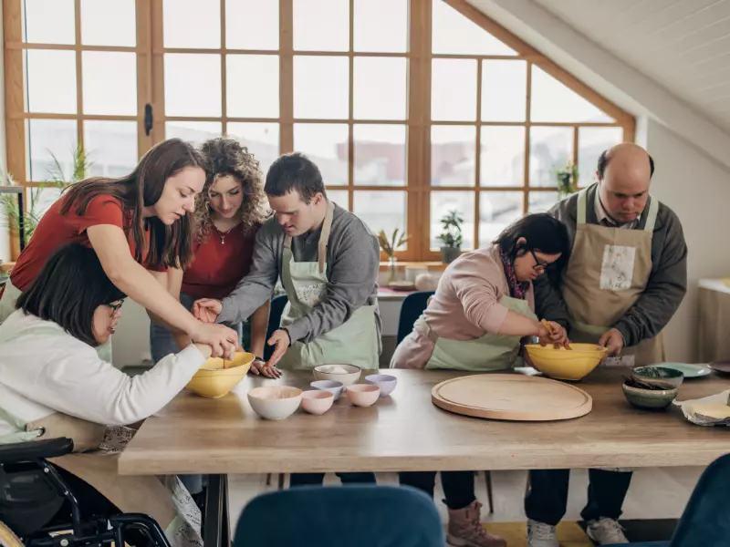 Disabled group of friends with down syndrome enjoying a cooking class with two carers