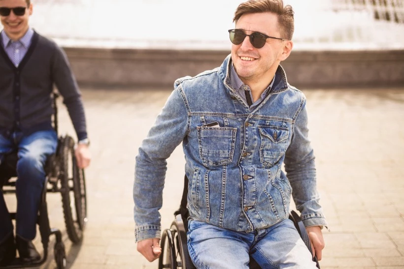 Two disabled male friends in wheelchairs smiling
